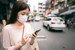 mujer soltera asiática joven de negocios usa máscara para el virus corona o covid19 en la ciudad al aire libre foto