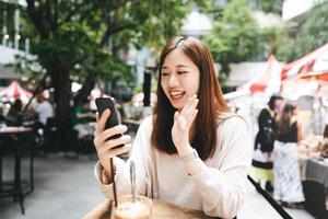 una mujer asiática de negocios adulta joven usa una tableta para hacer negocios en un café al aire libre