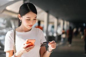 Consumidor de mujeres asiáticas de negocios de adultos jóvenes que usa tarjeta de crédito y teléfono inteligente para comprar en línea.