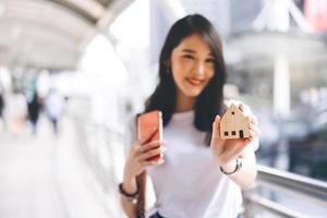 Focus on home wooden model holding by blur asian business woman. photo