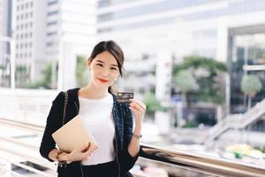 Happy young adult asian woman consumer using creadit card and digital tablet for shopping. photo