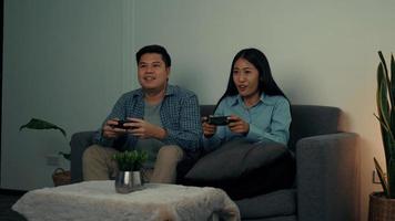 Asian couples are having fun playing games in their living room at night. photo