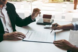 la mano del agente inmobiliario pasa la llave a los nuevos propietarios en la oficina con el concepto de casa del comprador.