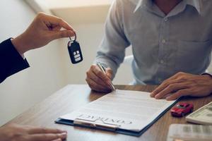 los compradores de automóviles nuevos firman documentos de contrato para compras de automóviles nuevos en la sala de exposición, la oficina del vendedor.
