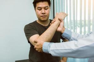 Los fisioterapeutas asiáticos revisan los codos de los pacientes que se han sometido a rehabilitación ortopédica. foto
