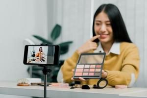 Asian teenage girls doing makeup vlogs and using a video mobile camera to record vlogs and publish them online at home. photo