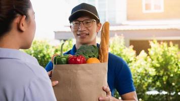 Delivery of an asian man handling a bag of food to a female customer at the door. photo