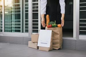 Asian woman open the door and took the bag of food ordered by the carrier to put in front of the house to prevent the epidemic. photo