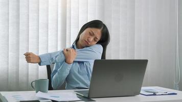 las jóvenes asiáticas estiran los músculos mientras se sientan en la oficina para relajarse del estrés. foto