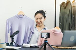 Young asian entrepreneurs are picking up their clothes to show off to customers through online sales on a live phone. photo