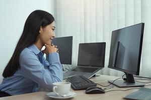 Asian woman software developers sitting in front of computers looking at computer codes on the screen. photo