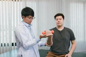 Asian physiotherapists are helping patients lift dumbbells for arm recovery. photo