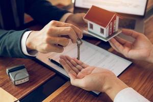 la mano del agente inmobiliario pasa la llave a los nuevos propietarios en la oficina con el concepto de casa del comprador.