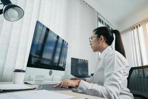 los desarrolladores de software asiáticos están analizando juntos el código escrito en el programa en la computadora en la sala de oficina. foto
