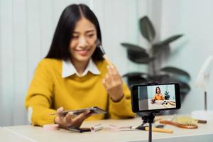 Asian teenage girls doing makeup vlogs and using a video mobile camera to record vlogs and publish them online at home. photo