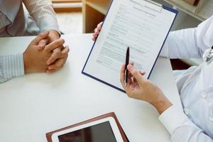 Confident female doctor reviews patient medical information and pointing to medical forms. photo