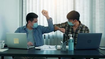 Asian colleagues in the office greet alternatives to avoid a handshake during the COVID-19 outbreak. photo