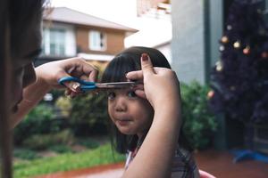 Mom was cutting her hair for her daughter at home. photo