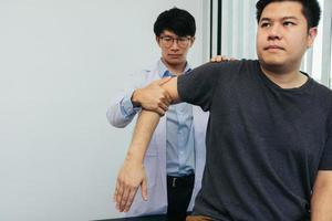 Physical therapists press to the patient shoulder check for pain. photo