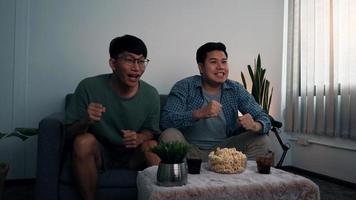 Asian male friends sit and win their favorite team that is broadcasting live football matches. photo