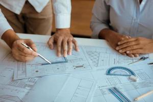 Architects engineer working with blueprints on table and discussing project together at the meeting in the office. photo