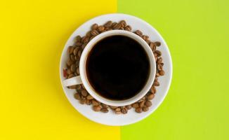 Top view, A cup of black coffee with coffee beans on yellow green background. photo