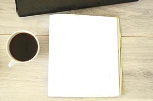 A cup of coffee, empty place in journal and notebook on wooden table, mockup photo