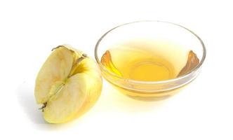 a half of an apple and a bowl with apple cider vinegar. photo