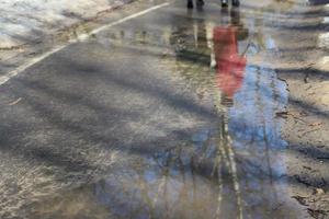 Early spring. Park alley. People silhouettes  and trees reflect in pools photo