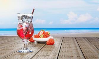 Mocktail Strawberry Soda not mix alcohol. Fresh strawberries in ceramic bowl in the background blur on plank wood table. Restaurant at beach and sea. Cool juice drinks with ice cubes. 3D Rendering. photo