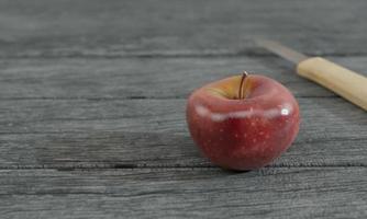 Manzana roja y mango de madera de cuchillo pequeño borroso en superficie de madera gris por renderizado 3d foto