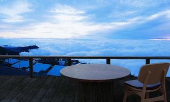 mesa y silla de madera en la terraza de madera en el restaurante de la cima de la montaña hay un mar de niebla en el fondo. mar de niebla, atracción turística phu thap berk, tailandia representación 3d foto