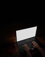 The hand of a person using a notebook or laptop, a blank screen, white, dark background, blacklight shines down on the hand. Mystery operation or hacker.3D Rendering photo