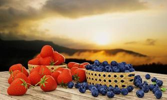 fresas y arándanos frescos en una cesta de bambú. las bayas se colocan sobre una superficie de madera. tiene un fondo de intrincados paisajes montañosos y luz solar, sol de la mañana y niebla. representación 3d foto