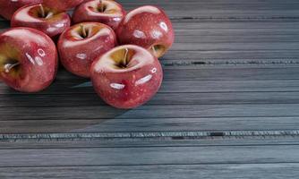 muchas manzanas rojas frescas colocadas sobre una mesa de madera. representación 3d foto