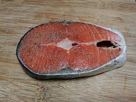 Fresh salmon fillets cut into pieces, seasoned with salt and ground pepper to make a fish steak. Put on a chopping block photo