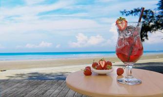 Mocktail Strawberry Nectar with Soda Does not mix alcohol. Fresh strawberries in a ceramic cup are in the background blur placed on a plank table. The restaurant at the beach and sea .3d rendering