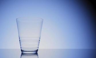 Representación 3D de un vaso de agua vacío en una superficie brillante con reflejo foto