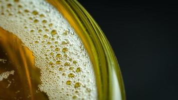 burbujas de aire o espuma en la superficie frontal de la cerveza en el vaso. el vaso de cerveza tiene agua y burbujas en el borde del vaso. foto