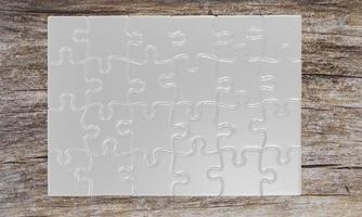 white blank jigsaw puzzle with shadows on a wood floor with cracks. 3D Rendering photo