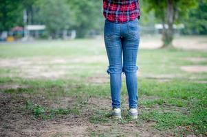 chica de pierna de pie en una zona verde. piernas para usar pantalones de pie y hay un espacio de copia. foto