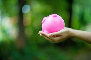 Female hand holding pink piggy bank, piggy bank and happy with savings. And copy space photo