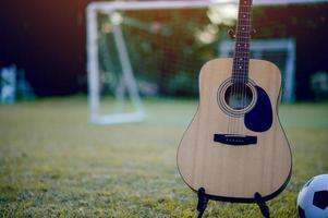 Guitar and football are placed in green lawns. Music and sports ideas And there is a copy space. photo