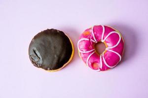 rosquillas de chocolate y rosquillas cubiertas con chocolate y espolvoreadas con rosquillas. yacía sobre un fondo rosa. foto