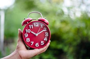 Creative flat flat concept Top view of a man's hand holding an antique red alarm clock on a bright green background with turquoise, with the smallest available copy space. photo