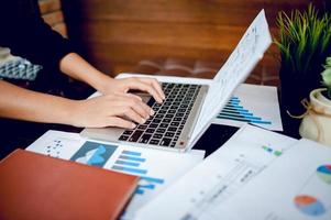 Young woman typing on  computer in a cafe. Business concept Business and graph paper Have copy space photo