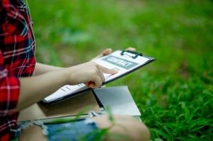 Hand of staff, marketing manager pointing to business documents and sitting under the tree - Business ideas photo