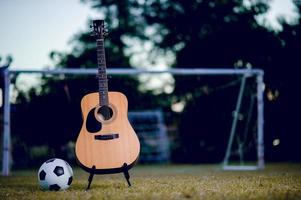 la guitarra y el fútbol se colocan en céspedes verdes. ideas de música y deportes y hay un espacio de copia.