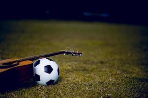 la guitarra y el fútbol se colocan en céspedes verdes. ideas de música y deportes y hay un espacio de copia. foto