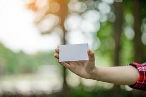 Girl holding a white business card. On a natural green background And there is a copy space. photo